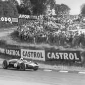 Crowds packed on grass banking to see Aussie Jack Brabham rounds one of the famous Silverstone bends during the Silver City Trophy race for Formula 1 cars in 1960. Photos: Getty Images