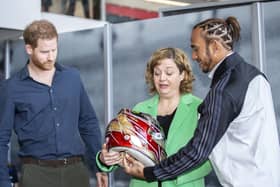 The Silverstone Experience chief executive Sally Reynolds accepts Lewis Hamilton's 2019 helmet alongside Prince Harry