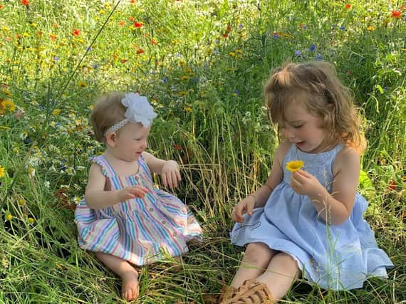 Sisters Jacey, three, and Evanna, 11 months, play in the flowers.