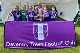 Daventry Town FC Pumas football team, Indi, Lucia, Isla, Amelie, Charlie, Ava, and Abbey, is celebrating with the Mayor of Daventry, Councillor Ted Nicholl.
