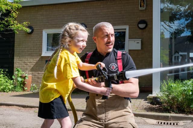 Firefighter Kieran Davies shows a young pupil at Staverton CoE Primary School the hose reels they use to put out fires