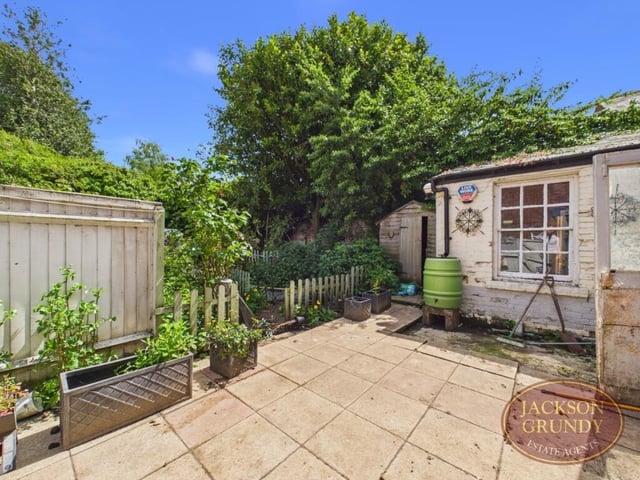 The private enclosed courtyard and walled garden features paved patio areas, mature shrubs, borders and trees