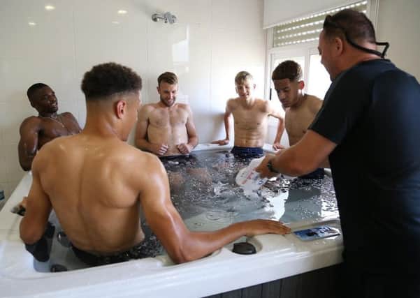 COOLING DOWN - Bob French puts the ice into the ice bath as Cobblers (from left) players Hakeem Odoffin, Shaun McWilliams, Andy Williams, Morgan Roberts and Jay Williams take a dip after Tuesday morning training (Picture: Pete Norton)