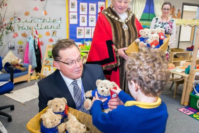 Mr Fall hands a pupil a teddy bear as Daventry Mayor Cllr Lynn Jones and headteacher Mrs Towers watch on