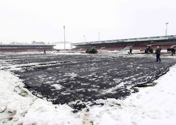 Cobblers supporters and staff clearing the pitch and surrounding areas of snow at Sixfields Stadium.