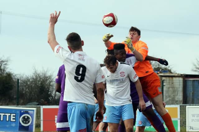 Lincoln United keeper Richard Walton punches clear from Daventry Town's Edilson Panzo-Antonio