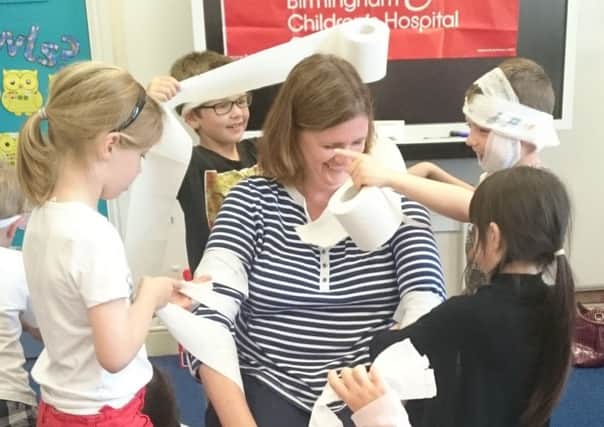 Children in Class 1 wrapping their teacher Mrs Andrew in toilet roll