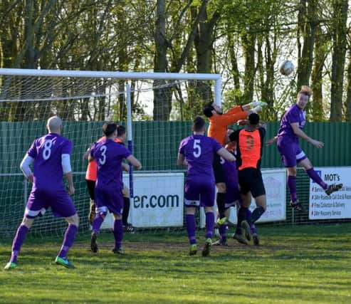 Daventry Town's Ross Harris heads clear from Wellingborough Whitworth attack to foil Cavel Jarvis
